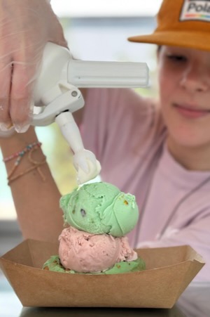 A Dreamboat server tops the donut off with whipped cream on top of two scoops of pistachio and strawberry ice cream. Photo by Andrea Ridout.